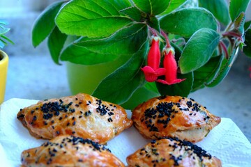 Homemade cheese and parsley pastries. Kohleria fuchsia in the background. Traditional Turkish breakfast pastries. Delicious pastries with black cumin. Ramadan iftar and sahur menu.