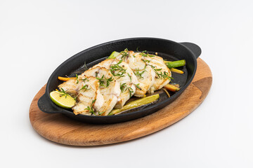 Grilled sea bass fillet served on skillet with vegetables