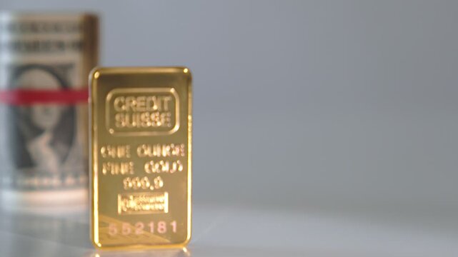 Pure one ounce gold bar from credit suisse bank with a roll of us dollar bills
