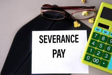 SEVERANCE PAY - words on a white sheet on a black envelope with a calculator and glasses