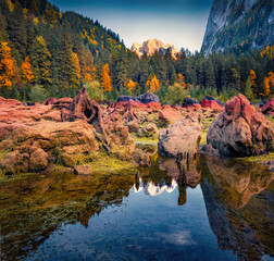 Exciting autumn scenery. Huge roots of cut trees on the shore of Gosausee (Vorderer) lake with Dachstein glacier on background. Spectacular morning scene of Austrian Alps, Upper Austria, Europe.