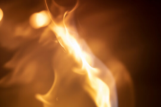 Abstract depiction of bright flames with blurred edges against a dark background creating a warm glow