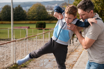 Father assisting his young son with movement practice or balance training outdoors, showing support and focused effort