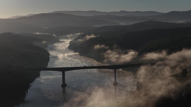 Cars passing the bridge over Douro river in the morning light with mist 