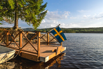 Swedish flag waving over lake pier in summer