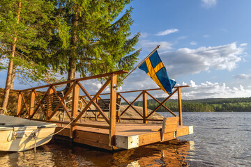 Swedish flag flying over wooden dock on serene lake