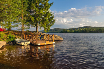 Swedish lake landscape with private wooden floating dock and moored boat