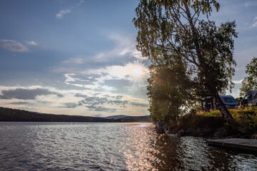 Sun shining over lake in Sweden with campers