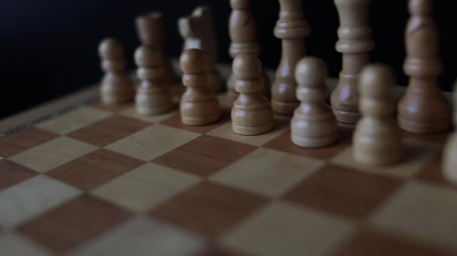 Dynamic video sequence of chess pieces positioned on a slowly rotating chessboard, symbolizing the intellectual confrontation between black and white opposing forces in strategic gameplay.