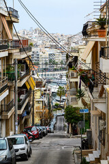 Grecja, Pireus. Wąska uliczka wiodąca w d&oacute;ł z dużą ilością element&oacute;w infrastruktury miejskiej