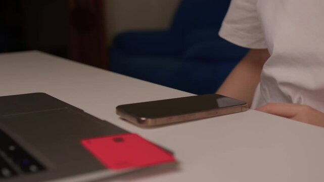 Hidden transaction amid dim lighting, Suspicious handoff between devices under low light, Scene depicting covert credit card transfer warning about online fraud risks
