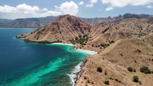 Scenic overhead aerial landscape of Komodo Island&rsquo;s Pink Beach surrounded by lush green hills