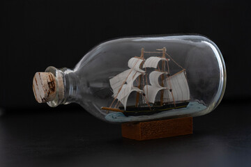 Ship in a Bottle. Small ship model in a bottle with a cork stopper on black background.