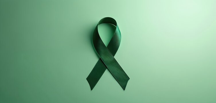 A dark green awareness ribbon lies on a soft green background. This symbol promotes mental health and self-care awareness. It signifies hope, support, and positivity.