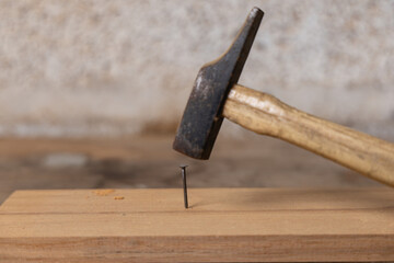 Un marteau frappe un clou pour l’enfoncer dans une planche de bois.