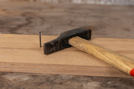 Un marteau en train d'enfoncer un clou sur une planche de bois.