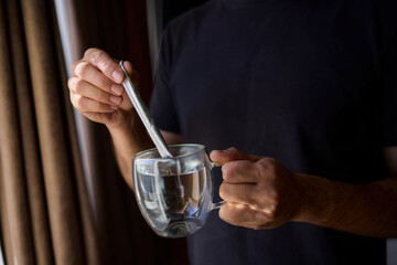 Warm tea preparation, Relaxed moment with steaming hot beverage in tranquility, Quiet domestic setting emphasizing mindful hand movements during tea stirring activities
