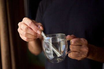 Warm tea preparation, Relaxed moment with steaming hot beverage in tranquility, Quiet domestic setting emphasizing mindful hand movements during tea stirring activities