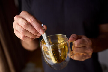Warm tea preparation, Relaxed moment with steaming hot beverage in tranquility, Quiet domestic setting emphasizing mindful hand movements during tea stirring activities