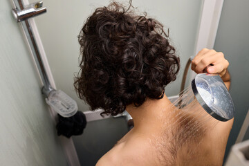 Close view of man washing hair thoroughly, Man under shower rinses hair closely while grooming himself, Detailed shot of man cleansing his hair with water under shower