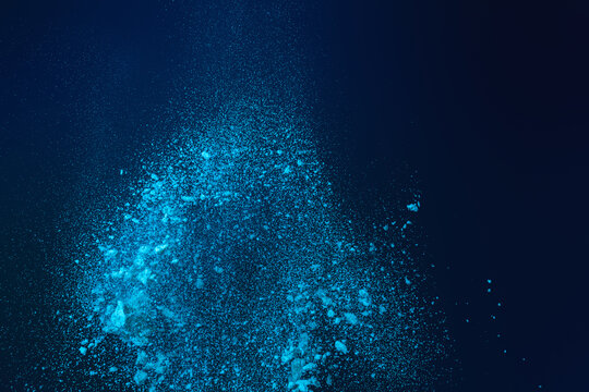 Dynamic Explosion of Vibrant Blue Powder Particles Scattering Against a Dark Background