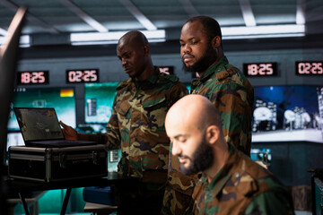 Military agents in war room operating satellite system to support reconnaissance and target...