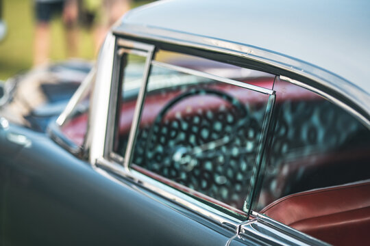 Classic car window detail with red interior and chrome trim