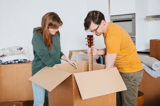 Couple Packing Guitar Into Cardboard Box, Moving Day - Powered by Adobe