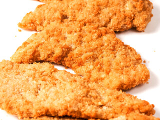 Uncooked chicken goujons or tenders in on white background. Popular classic chicken dish made from pieces of breast and breadcrumbs. Traditional ready to cook poultry product.