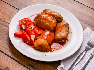 Plate with traditional Russian cabbage rolls with fresh tomato and juicy red sauce. Popular folk food with all kind of stuffing inside.