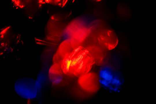 A blurry image of red lights and a yellow light. The red lights are scattered throughout the image, creating a sense of movement and energy. The yellow light is in the center of the image - Powered by Adobe