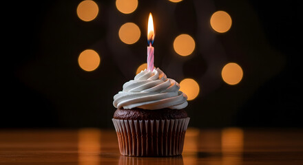 A freshly baked cupcake with a glowing birthday candle