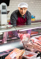 Young male butcher showing big piece of beef meat in butchery