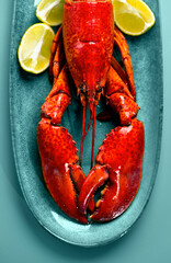 Lobster seafood, gourmet food. Whole steamed lobster with lemon on a blue plate, top view, flat lay, from above. Aesthetics, Vertical art design photo, close up