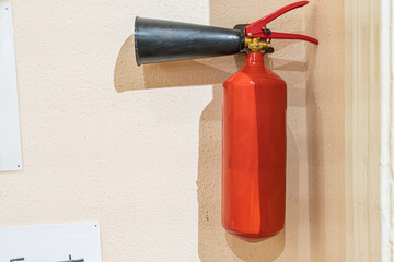 Centrally located red fire extinguisher on beige wall, toy car on top, soft lighting, vibrant...