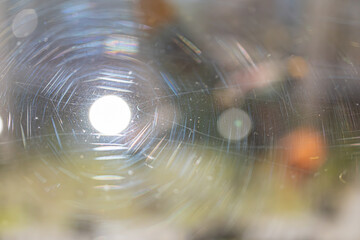A close-up view of light shining through a distorted transparent medium, with radial lines caused by lens flare and scattering due to ripples and particles