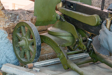 Industrial machine in use, greenish-blue paint, levers, handles, dial, human interaction, rocky...
