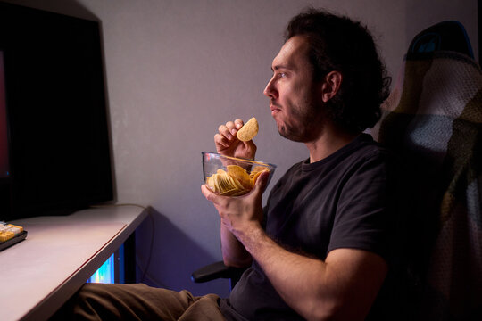 Programmer enjoying late night snack, Individual working alone in home office environment, Solitary male professional grubbing on sandwich during late hours at his desk