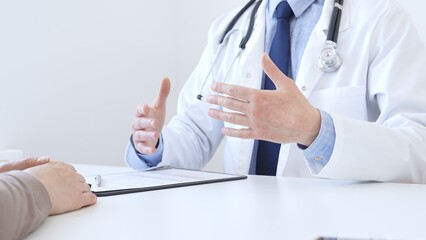 Adult doctor gesturing with hands while explaining diagnosis to patient during medical consultation in hospital office, healthcare and medical concept. Medicine concept