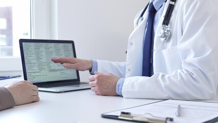 Doctor reviewing digital test results with patient, discussing health findings on laptop screen during clinical consultation. Medicine and health care concept.