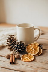 A still life composition of dried oranges, cinnamon, pine cones and a mug on a wooden table.