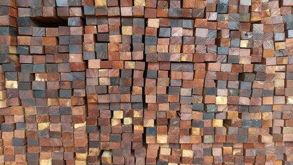 A close-up of neatly stacked wooden blocks showing natural brown, yellow, and dark wood textures. This photo is perfect for backgrounds, construction concepts, timber industry promotions, or interior 