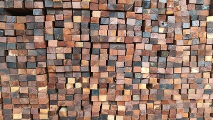 A close-up of neatly stacked wooden blocks showing natural brown, yellow, and dark wood textures. This photo is perfect for backgrounds, construction concepts, timber industry promotions, or interior 