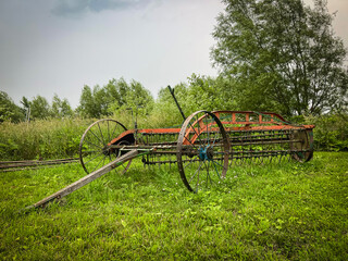 Old horse drawn hay rake in a grassy field. These are still used today by the Amish to collect hay or straw into windrows. Found in the heart of Illinois Amish Country - Arthur, Illinois.
