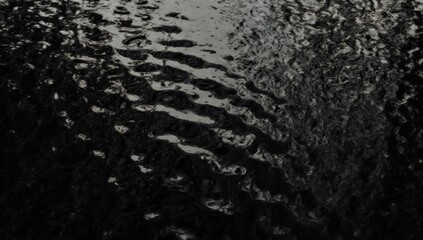 Obraz premium Rippling dark water surface, reflecting light, with textural undulation