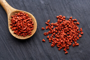 Bixa Orellana - Organic red annatto seeds on a spoon and scattered on the bottom