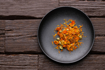 Organic calendula petals in a dark bowl - Calendula officinalis