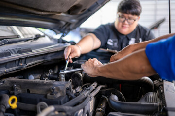 Mechanics repairing car engine together in auto garage