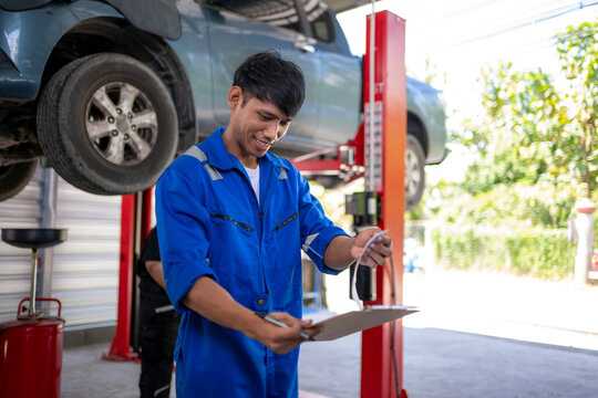 Smiling mechanic checking car service checklist in garage