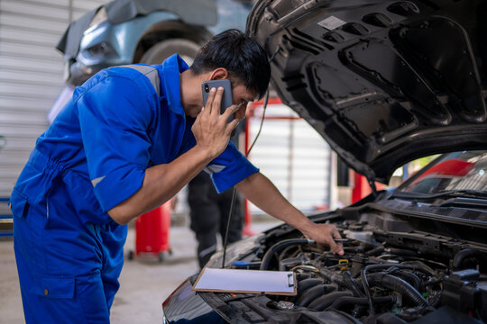 Mechanic talking on phone checking car engine